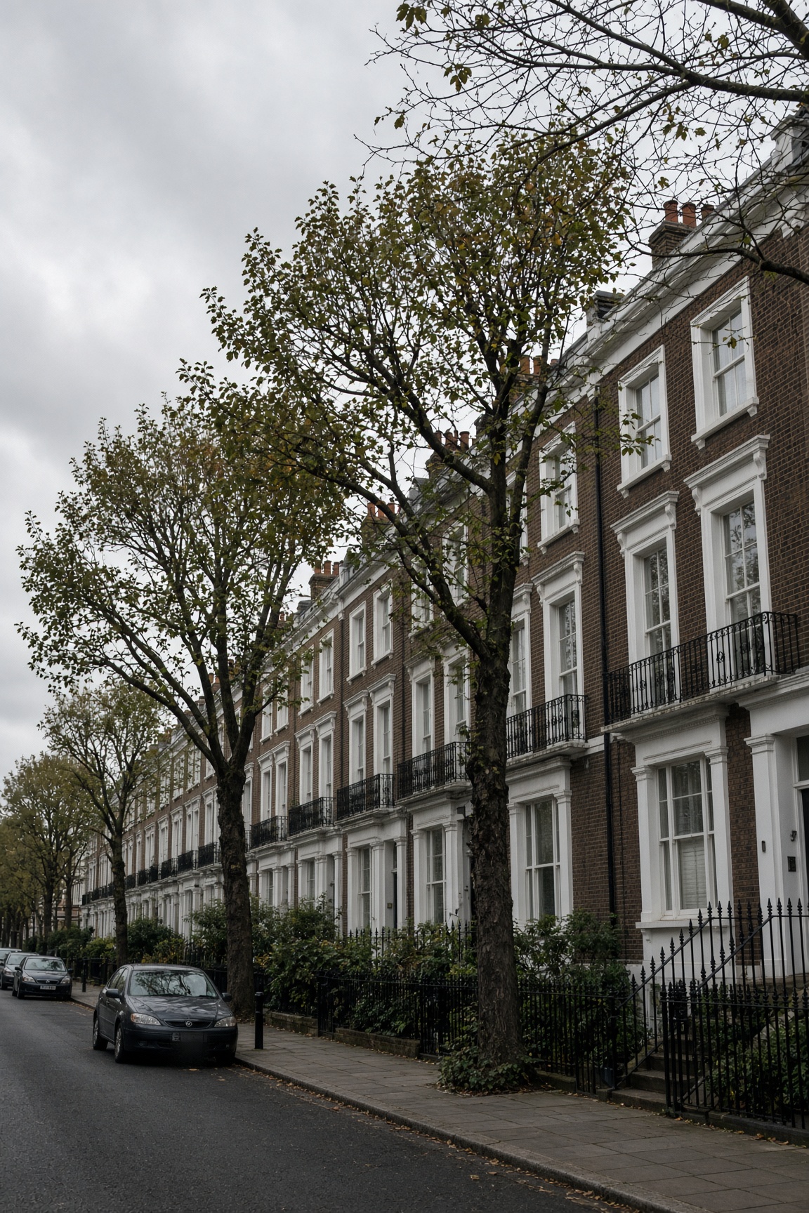 A terrace of brick London houses with white sash windows, under an overcast sky